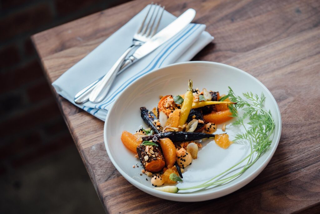 Vegan dish of roasted vegetables in a white dish on a wooden table
