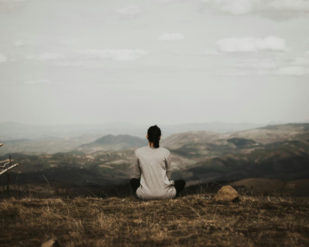 Woman meditating on top of a hill.