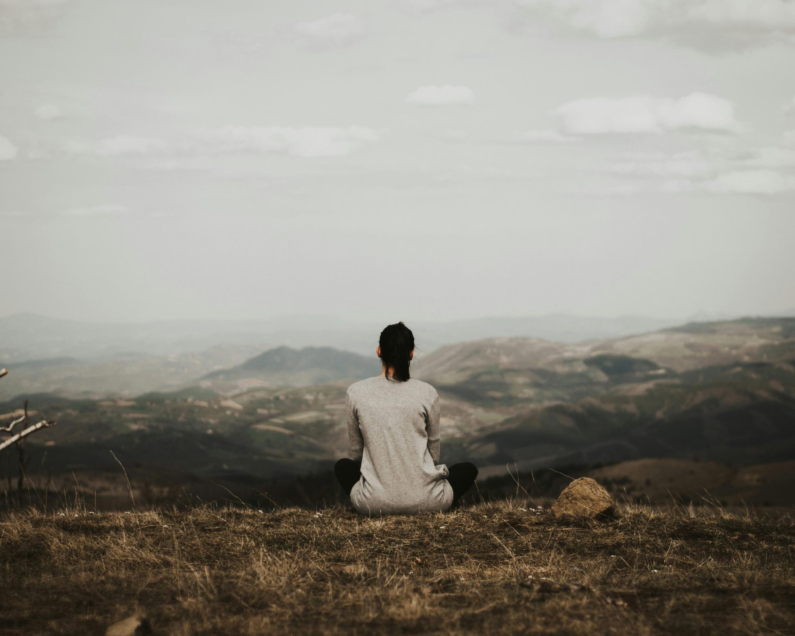 Woman meditating on top of a hill.